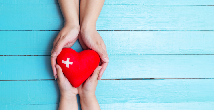 two sets of hands holding a cartoon heart, against a blue background