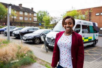 Woman standing outside a hospital in front of an ambulance