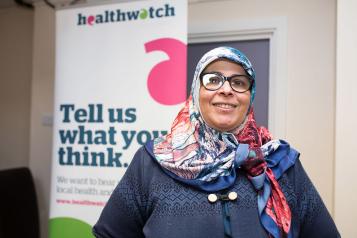 Woman standing in front of a banner that says "tell us what you think"