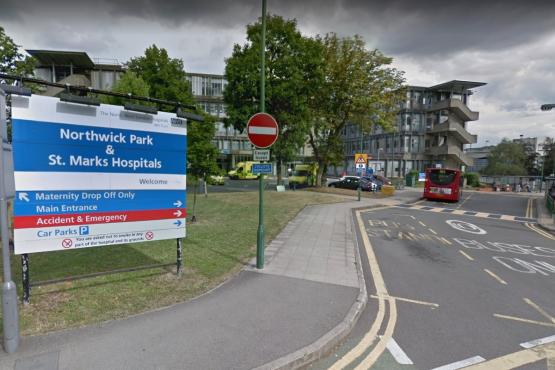 This is a picture of outside of Northwick Park Hospital. On the left hand side is a grass area and the blue sign is saying 'Northwick Park & St Marks'