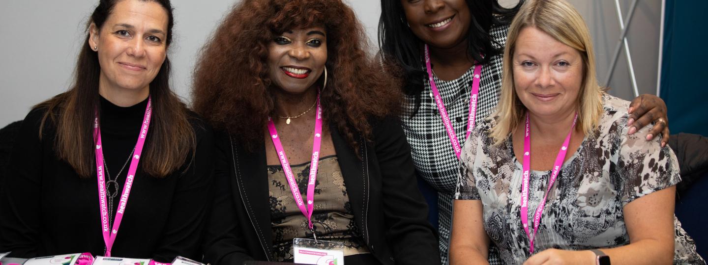 four women sitting behind a desk full of name badges